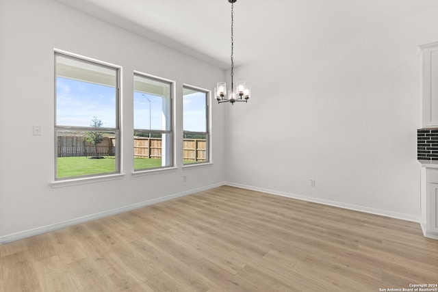 unfurnished dining area featuring a chandelier, light hardwood / wood-style floors, and a healthy amount of sunlight