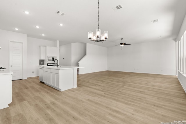 kitchen featuring ceiling fan with notable chandelier, light wood-type flooring, white cabinetry, and hanging light fixtures