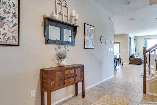 hall featuring a textured ceiling and light tile patterned floors