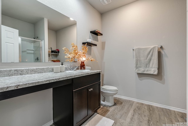 bathroom with vanity, toilet, hardwood / wood-style floors, and a shower with door