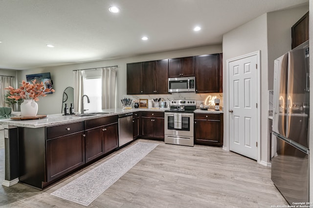 kitchen featuring kitchen peninsula, stainless steel appliances, sink, and light hardwood / wood-style floors