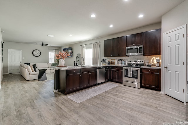 kitchen with appliances with stainless steel finishes, light hardwood / wood-style floors, sink, kitchen peninsula, and ceiling fan