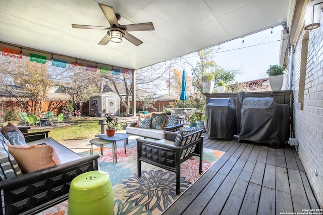 wooden terrace with an outdoor living space, a grill, ceiling fan, and a shed