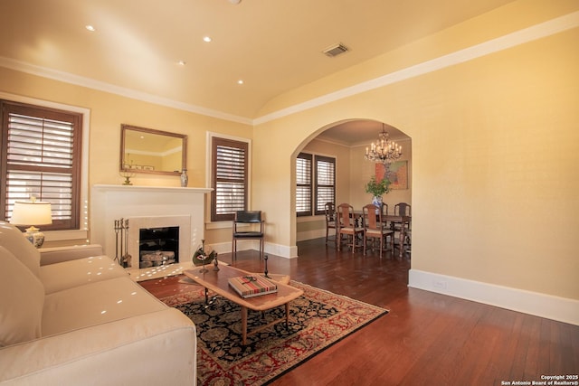 living room with dark wood-type flooring, ornamental molding, lofted ceiling, and a notable chandelier