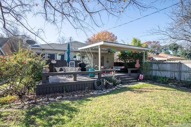 rear view of house featuring ceiling fan, a yard, and a deck