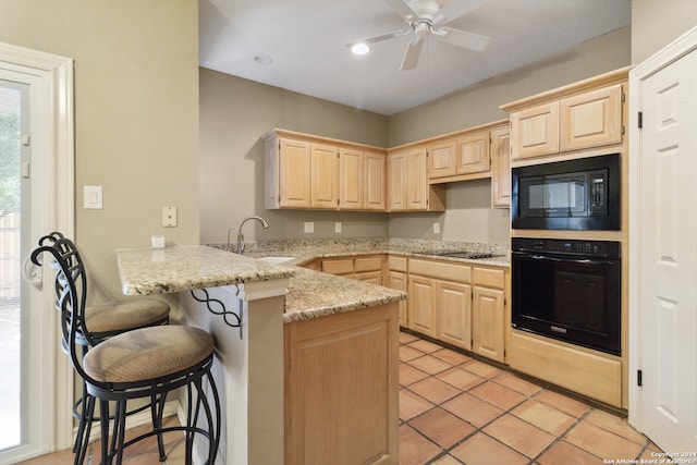 kitchen featuring light stone countertops, black appliances, a kitchen bar, kitchen peninsula, and light brown cabinets