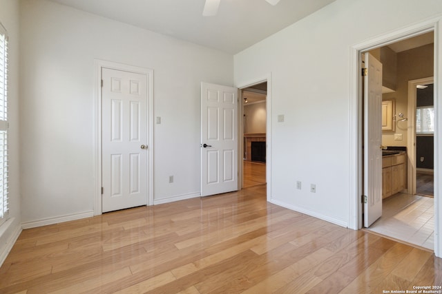 unfurnished bedroom with light hardwood / wood-style flooring, connected bathroom, and ceiling fan