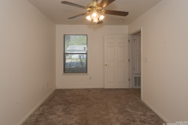 spare room featuring dark carpet and ceiling fan