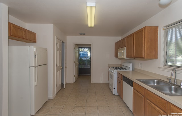 kitchen featuring sink, light tile patterned floors, and white appliances