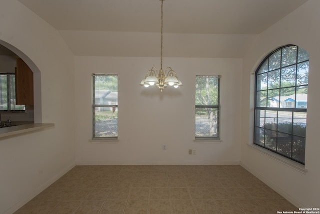 unfurnished dining area featuring a wealth of natural light, a notable chandelier, and light tile patterned flooring