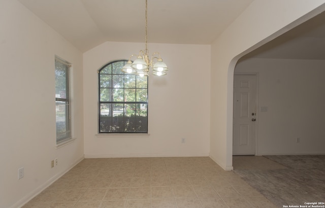 empty room with light tile patterned floors, an inviting chandelier, and vaulted ceiling