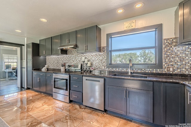 kitchen with backsplash, sink, appliances with stainless steel finishes, and dark stone counters