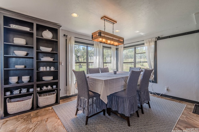 dining space with a barn door and a textured ceiling