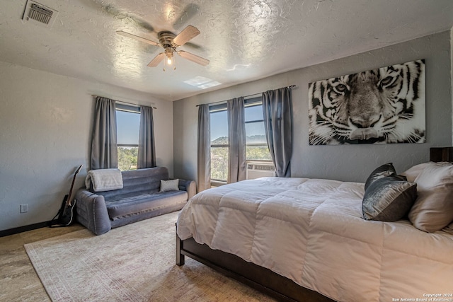 bedroom featuring a textured ceiling, light hardwood / wood-style flooring, cooling unit, and ceiling fan