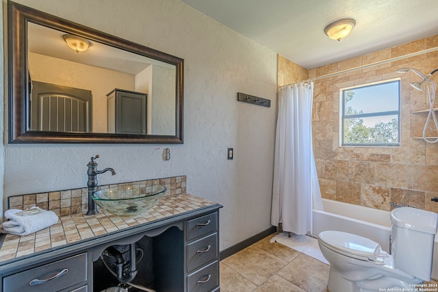 full bathroom with tile patterned flooring, toilet, vanity, shower / bath combo with shower curtain, and a textured ceiling