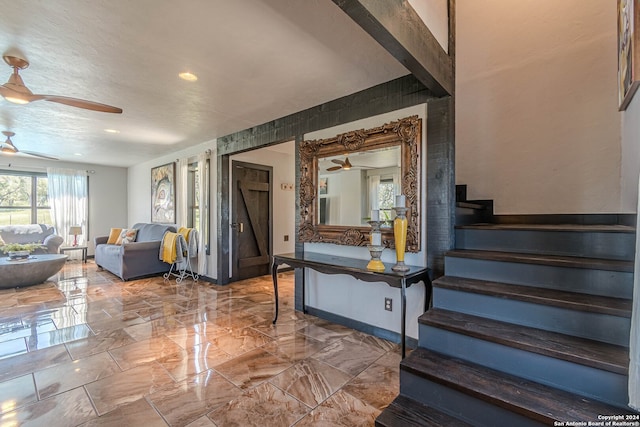 stairway featuring ceiling fan and a textured ceiling