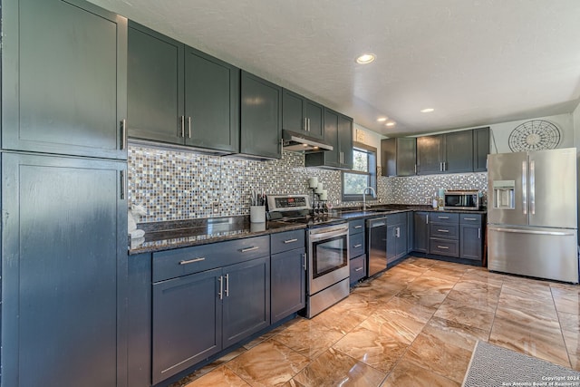 kitchen with dark stone counters, tasteful backsplash, a textured ceiling, stainless steel appliances, and sink