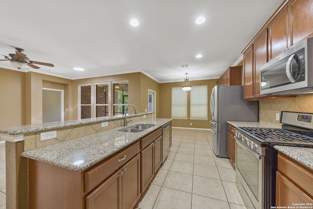 kitchen featuring decorative light fixtures, appliances with stainless steel finishes, a kitchen island with sink, sink, and ceiling fan