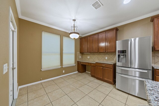 kitchen with built in desk, stainless steel fridge, light stone counters, and ornamental molding