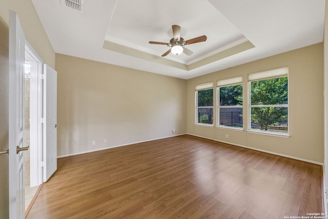 spare room with a tray ceiling, crown molding, wood-type flooring, and ceiling fan