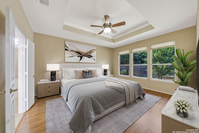 bedroom featuring a tray ceiling, light wood-type flooring, and ceiling fan