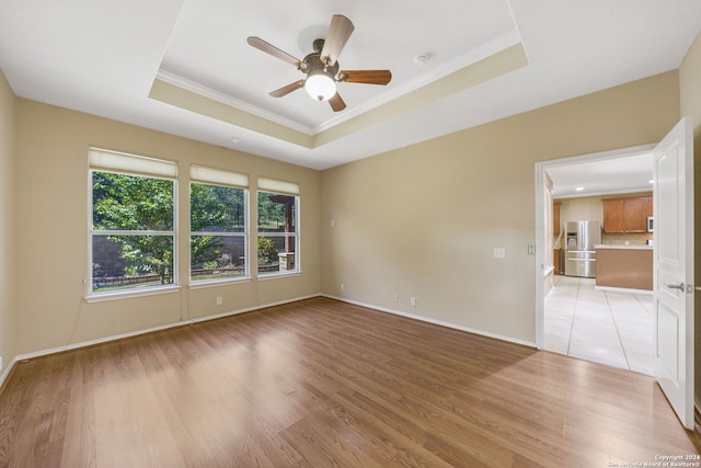 spare room featuring ceiling fan, a raised ceiling, light hardwood / wood-style floors, and ornamental molding