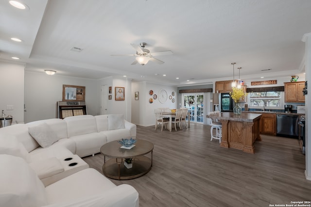 living room featuring dark wood-type flooring, ceiling fan, crown molding, and sink