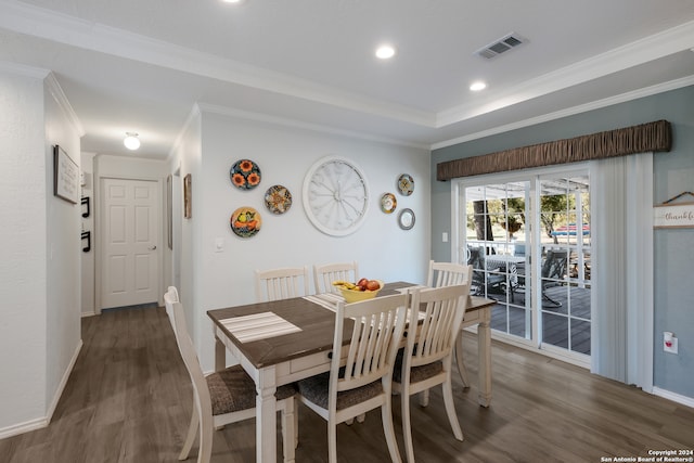 dining space featuring crown molding, a raised ceiling, and dark hardwood / wood-style flooring