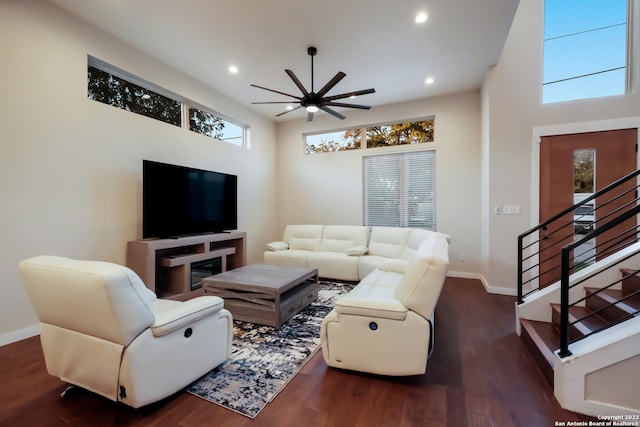 living room featuring dark hardwood / wood-style flooring, a wealth of natural light, a high ceiling, and ceiling fan