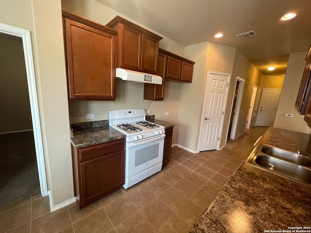 kitchen featuring dark tile patterned flooring, sink, and white range with gas cooktop