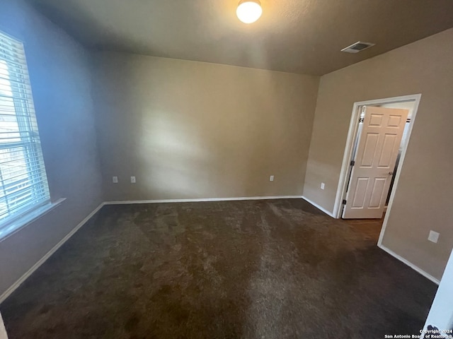 spare room with dark colored carpet