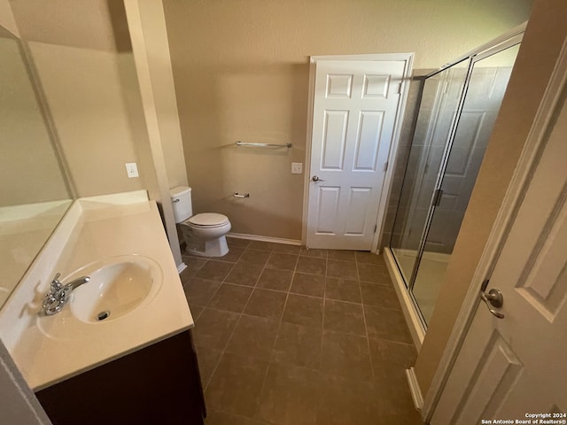 bathroom with vanity, toilet, tile patterned floors, and a shower with door