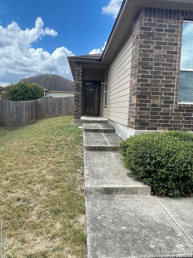 view of exterior entry featuring a yard