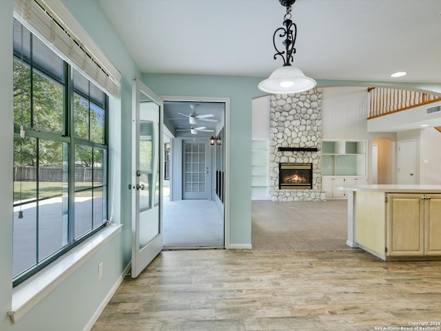 kitchen featuring a fireplace, pendant lighting, light hardwood / wood-style flooring, and ceiling fan