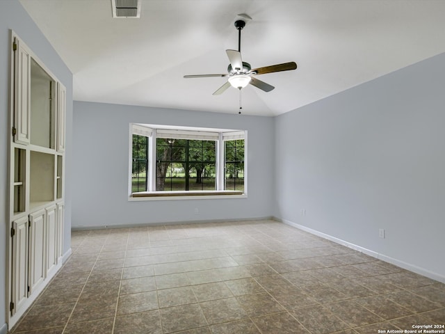 spare room with ceiling fan, light tile patterned floors, and vaulted ceiling