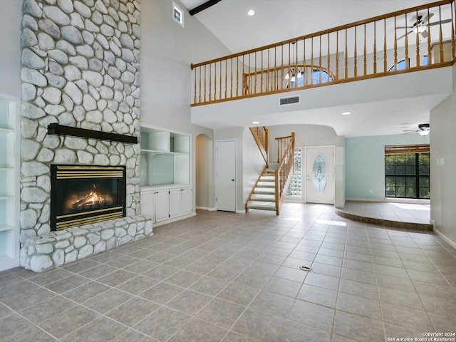 unfurnished living room featuring high vaulted ceiling, ceiling fan, light tile patterned floors, and a stone fireplace