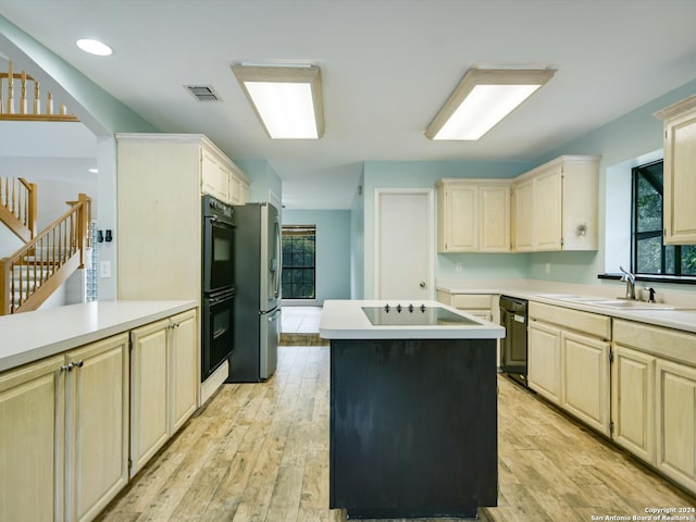 kitchen with a kitchen island, cooktop, light hardwood / wood-style floors, stainless steel refrigerator, and sink