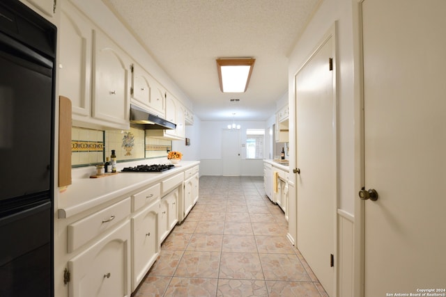 kitchen with gas stovetop, decorative backsplash, an inviting chandelier, white cabinets, and a textured ceiling