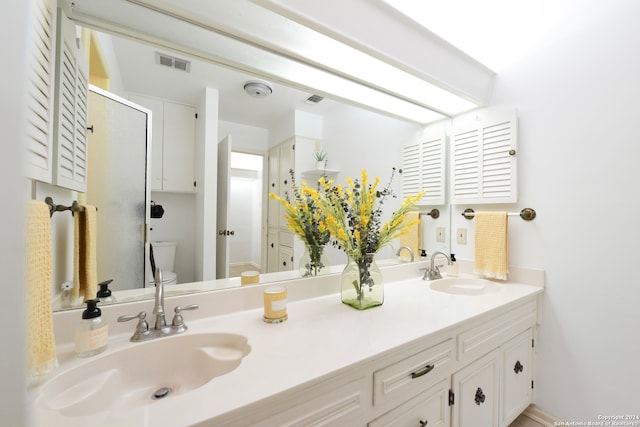 bathroom featuring toilet, walk in shower, and vanity