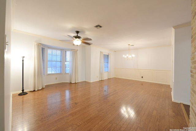 spare room featuring crown molding, wood-type flooring, and ceiling fan with notable chandelier