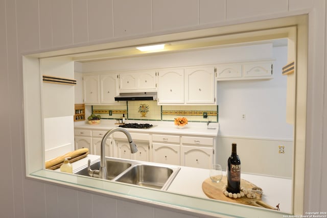 kitchen with decorative backsplash, white cabinetry, sink, and gas cooktop