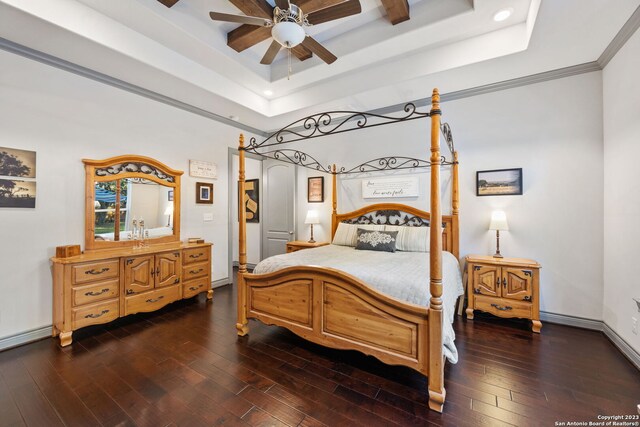 bedroom with ornamental molding, dark hardwood / wood-style flooring, a tray ceiling, and ceiling fan