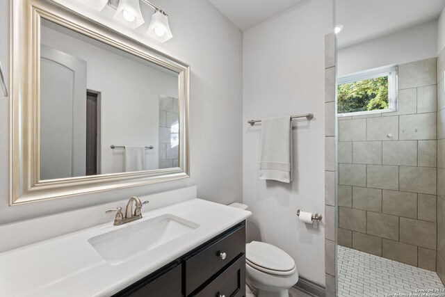 bathroom with tiled shower, vanity, and toilet