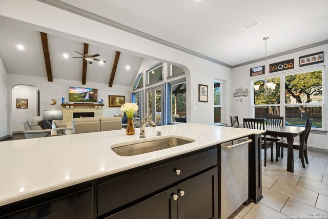 kitchen featuring pendant lighting, stainless steel dishwasher, sink, lofted ceiling with beams, and ceiling fan