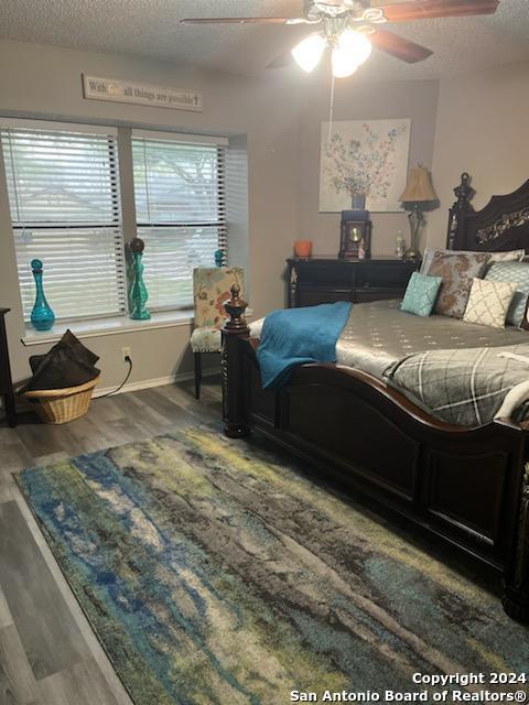 bedroom with a textured ceiling, hardwood / wood-style floors, and ceiling fan