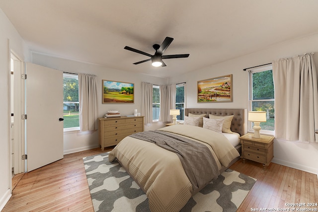 bedroom with multiple windows, ceiling fan, and light hardwood / wood-style floors