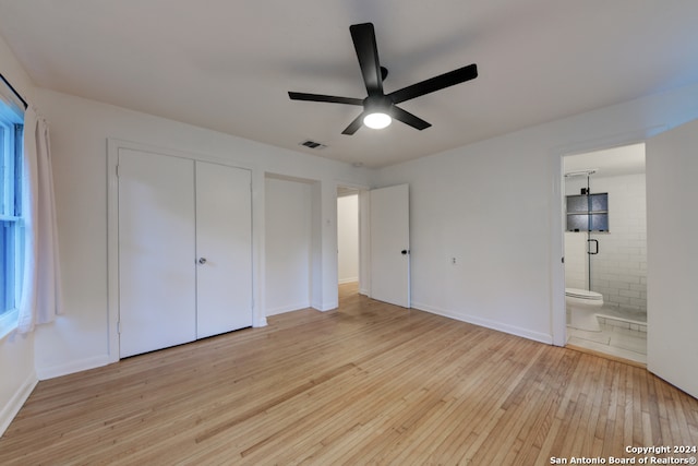 unfurnished bedroom featuring ensuite bath, light hardwood / wood-style flooring, ceiling fan, and a closet