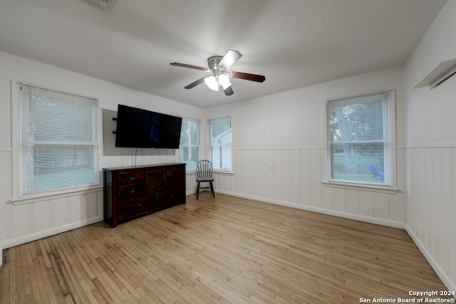 unfurnished living room featuring light wood-type flooring, a wealth of natural light, and ceiling fan