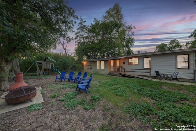 yard at dusk featuring a fire pit and a playground