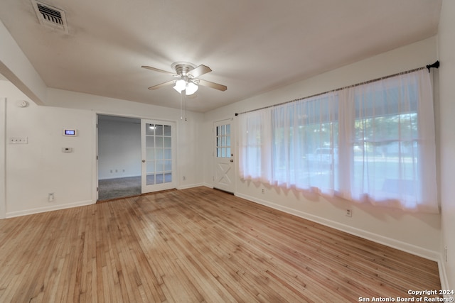 spare room featuring light wood-type flooring, ceiling fan, and plenty of natural light